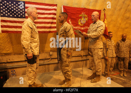 Sergeant Maj. Micheal Barrett, right, the 17th Sergeant Major of the Marine Corps, reads the meritorious promotion warrant of Lance Cpl. Miguel Mercedes, an ammunition technician specialist with Redeployment and Retrograde in support of Reset and Reconstitution Operations Group, during his meritorious promotion ceremony aboard Camp Leatherneck, Afghanistan, Sept. 6, 2014. General James F. Amos, the 35th Commandant of the Marine Corps, meritoriously promoted Mercedes, a native of Bronx, New York, to the rank of corporal during his final visit to Helmand province. Commandant, Sergeant Major of t Stock Photo