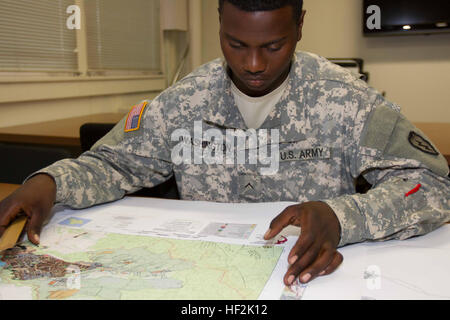 Private Jerall Washington studies a few maps to ensure they spacing and placement of grid lines is accurate after an interview about receiving a phone call from the Secretary of the Army, John M. McHugh. On Oct. 17, 2014, the Secretary of the Army called and congratulated Washington on overcoming his impairments of severe eyesight and hearing loss and his successful enlistment in the Army. (U.S. Army photo by Staff Sgt. Matthew G. Ryan, 25th Inf. Div. Public Affairs NCO) Soldier overcomes disabilities to fulfill his dream 171014-A-ZE044-006 Stock Photo