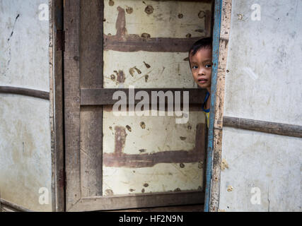 A young Filipino boy peeks out of the doorway of his home in Tacloban, Leyte, Philippines, Nov. 16, 2014. A year after the relief and recovery efforts of Operation Damayan, following the catastrophic destruction caused by Super Typhoon Yolanda across portions of the Philippines, the people of Tacloban, one of the hardest hit areas, have continued to show their resiliency as they make every effort of returning to a normal way of life. (U.S. Marine Corps photo by MCIPAC Combat Camera Staff Sgt. Jeffrey D. Anderson/ Released) Commemoration of Op Damayan, 2014 141116-M-WN441-716 Stock Photo