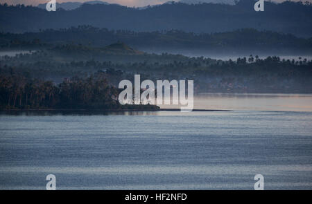 A thin layer of fog hangs over the mountains across the Cancabato Bay near the Tacloban City Port in Tacloban, Leyte, Philippines, during the early morning hours Nov. 18, 2014. A year after the relief and recovery efforts of Operation Damayan, following the catastrophic destruction caused by Super Typhoon Yolanda across portions of the Philippines, the people of Tacloban, one of the hardest hit areas, have continued to show their resiliency as they make every effort of returning to a normal way of life. (U.S. Marine Corps photo by MCIPAC Combat Camera Staff Sgt. Jeffrey D. Anderson/ Released)  Stock Photo