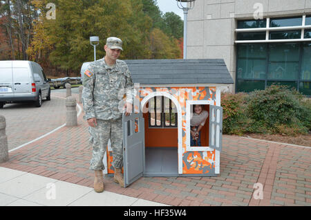 Army Sgt. Marc Hillhouse, administrative sergeant and an 11-year active Guard reservist of the North Carolina National Guard's E Company, 1-130th Attack Reconnaissance Battalion, and his 6-year-old daughter Millie take a moment to get a shot of a playhouse donated by Glaxo Smith Kline Institute and Habitat for Humanity organizations in Research Triangle Park, N.C., earlier this month. The gift, a life-sized play house, was an early birthday present for Millie and was part of GSK's donation in recognition of Year of the Child, 2013. Five other charity organizations to include Genesis Home in Du Stock Photo