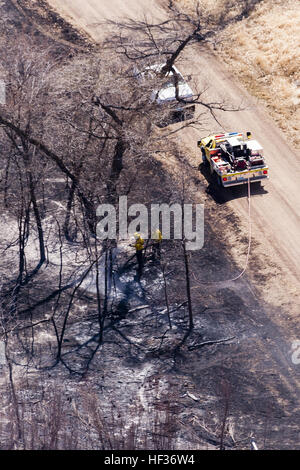 The day after a large fire threatened homes and property in Burleigh County, smoldering wood and high winds were still a concern for firefighters and homeowners. The fire began just south of Bismarck and the North Dakota National Guard helicopters dropped hundreds of loads of water from the air while local fire departments worked many hours on the ground getting the fire under control. (National Guard photo by Chief Warrant Officer 4 Kiel Skager, N.D. National Guard Joint Force Headquarters/Released) South Burleigh County Wildfire response 041415-Z-BU745-130 Stock Photo