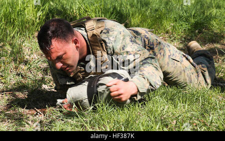 Sergeant John Williams, a Marine attending a martial arts instructor course with Black Sea Rotational Force, low-crawls with his sandbag April 24, 2015, at Mihail Kogalniceanu Air Base, Romania. During the final culminating event, the Marines carried a sandbag that, unknown to them, had their new Marine Corps Martial Arts Program belt in it. Marines earn MCMAP instructor tab 150424-M-EG384-313 Stock Photo