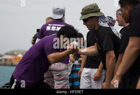 Master Sgt. Jason A. Annis, data chief with Headquarters & Headquarters Squadron, Marine Corps Air Station Futenma assists an Okinawa resident up a ladder May 5 during the 41st annual Naha City Dragon Boat Races, also known as Harii, at Tomari Port in Naha City, Okinawa. More than 60 teams competed in the races, making a total of approximately 2,300 participants. Three teams, consisting of 32 people per boat, competed against each other in every race. The SMP dragon boat team was made up of approximately 44 Marines and sailors. “We all came out here to have fun,” said Annis. “We did win our fi Stock Photo