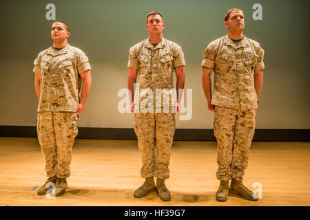 Lance Cpl. Maxwell Navarra (left), a squad leader with 1st Battalion, 2nd Marine Regiment, Cpl. Zachary Graybill (middle), an automotive organizational mechanic with the unit, and Petty Officer 3rd Class Travis Hippey (right), a corpsman also with the unit, stand at attention for the reading of the citations during a ceremony held at the base theatre aboard Camp Lejeune, N.C., May 6, 2015. “I think it’s important because you can read an award off to anybody and it’s pretty after-the-fact, but when you put three people, especially two of them who received wounds and now Purple Hearts, in front  Stock Photo