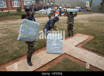 Nepalese service members gather relief aid delivered by a UH-1Y Huey helicopter with Joint Task Force 505 at an outlying village near Kathmandu, Nepal, May 7. The Nepalese government requested the U.S. government’s assistance after a 7.8 magnitude earthquake struck the country April 25. U.S. military services came together to form JTF 505, which works in conjunction with U.S. Agency for International Development and the international community, to provide unique capabilities to assist Nepal. (U.S. Marine Corps photo by MCIPAC Combat Camera Staff Sgt. Jeffrey D. Anderson) US Marines airlift rel Stock Photo