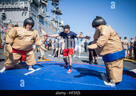 U.S. Marines and sailors with 31st Marine Expeditionary Unit (MEU) participate in sumo suit wrestling during the Fourth of July 'steel beach' picnic on the flight deck of the USS Bonhomme Richard (LHD 6), at sea, July 4, 2015. The MEU is currently conducting their annual Fall Patrol of the Asia-Pacific region. (U.S. Marine Corps photo by GySgt Ismael Pena/Released) Fourth of July celebration aboard the USS Bonhomme Richard 150704-M-CX588-007 Stock Photo