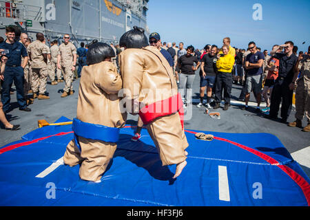 U.S. Marines and sailors with 31st Marine Expeditionary Unit (MEU) participate in sumo suit wrestling during the Fourth of July 'steel beach' picnic on the flight deck of the USS Bonhomme Richard (LHD 6), at sea, July 4, 2015. The MEU is currently conducting their annual Fall Patrol of the Asia-Pacific region. (U.S. Marine Corps photo by GySgt Ismael Pena/Released) Fourth of July celebration aboard the USS Bonhomme Richard 150704-M-CX588-034 Stock Photo