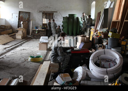 Colorado National Guardsmen remodel historic bulding in Slovenia. The 140th Wing Civil Engineers working in the storage area of the building they are remodeling during a morning rain shower. First Lt. Drew Lange uses his laptop computer on an improvised desk within the storage area of the building the 140th is remodeling. Plumbing work is going on in the background. Colorado construction in Slovenia 150713-Z-PY016-230 Stock Photo