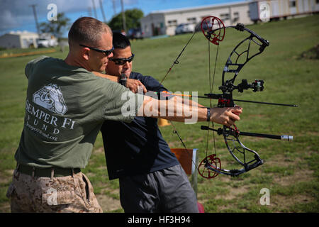 Staff Sgt. Charles Amerson, a section leader with the Wounded Warrior Battalion West-Detachment Hawaii and Tampa, Fla., native, assists Lance Cpl. Daniel McLinden, a service member recovering with the Wounded Warrior Detachment and Plaistow, N.H., native, with his shooting technique at the archery range aboard Marine Corps Base Hawaii, July 23, 2015. Every Tuesday and Thursday, service members with the detachment participate in activities such as archery, swimming, track, shooting and cycling as part of the Warrior Athletic Reconditioning Program. The purpose of WARP is to help service members Stock Photo