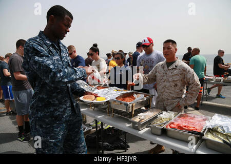 GULF OF ADEN (Aug. 29, 2015) U.S. Marines and Sailors from the 15th Marine Expeditionary Unit and Essex Amphibious Ready Group fill their plates with food at a steel beach picnic aboard the amphibious transport dock ship USS Anchorage (LPD 23). Elements of the 15th MEU are embarked aboard the Anchorage, which is part of the ESX ARG, and is deployed in support of maritime security operations and theater security cooperation efforts in the U.S. 5th Fleet area of operations. (U.S. Marine Corps photo by Sgt. Steve H. Lopez/Released) US Marines, Sailors enjoy steel beach picnic 150829-M-TJ275-042 Stock Photo
