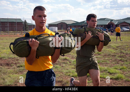 Two Naval ROTC midshipman candidates participate in a relay station at Camp Navajo, Arizona, during a New Student Orientation event. Candidates are divided into teams and rotate through multiple stations, completing physical and team-based challenges. The weeklong training involves joint exercises between the University of Arizona, University of New Mexico, and Arizona State University NROTC units in the Flagstaff area to develop skills in teamwork, endurance, and leadership. Stock Photo