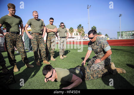 Staff Sgt. Joseph Mendoza, a non-lethal weapons instructor with Special Purpose Marine Air-Ground Task Force Crisis Response-Africa, stuns a Marine with the X26 Taser during non-lethal training at Naval Air Station Sigonella, Italy, Nov. 1, 2016. Marines completed a weeklong non-lethal course, which covered Taser training, OC exposure and riot control team tactics.  (U.S. Marine Corps photo by Cpl. Alexander Mitchell/released) No Pain, No Gain, Marines complete non-lethal training in Italy 161101-M-ML847-389 Stock Photo