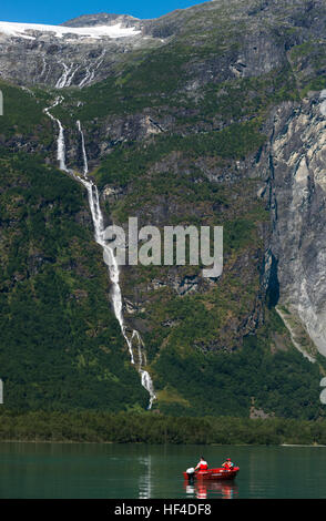 A view across Lovatnet Lake with a glacier melting into a waterfall. Norway. Stock Photo