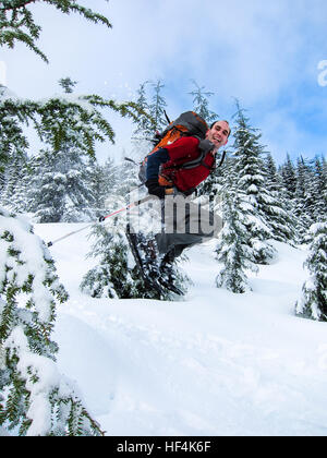A man having fun jumping through trees on snowshoes Stock Photo