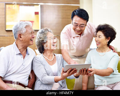 senior asian couples having a good time using tablet computer together. Stock Photo