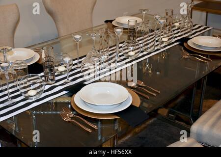 An elegant dinner set up prepared on a beautiful glass table for a formal holiday dinner Stock Photo