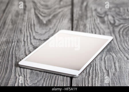 White tablet on a wooden table. Removed logos, buttons, change the original size. Stock Photo