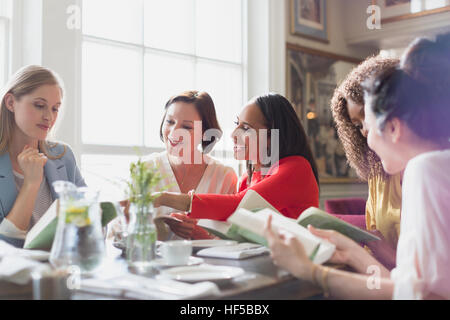 Women friends discussing book club book at restaurant table Stock Photo