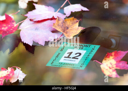 Autumn leaves and inspection sticker on the windshield of a car in Vermont's Green Mountains. Stock Photo