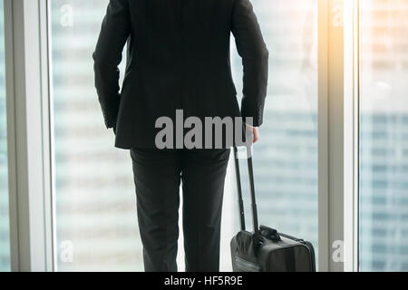 Businessman standing with suitcase near the window Stock Photo