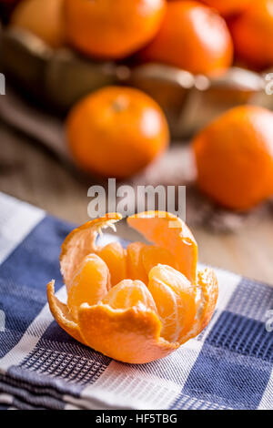 Tangerines, peeled tangerine and tangerine slices on a blue cloth. Mandarine juice. Stock Photo