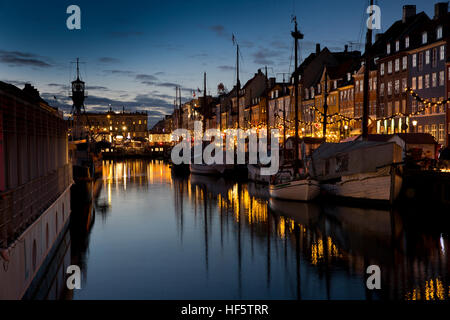 Denmark, Copenhagen, Nyhavn, winter, boats moored at quayside at night, reflected in water Stock Photo