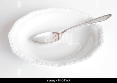 empty plate with silver spoon isolated on white background Stock Photo
