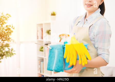 Smiling happy housewife ready prepared holding bucket fill up with detergent for cleaning home at living room. mixed race asian chinese model. Stock Photo