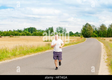 Fat man running on a rural road Stock Photo