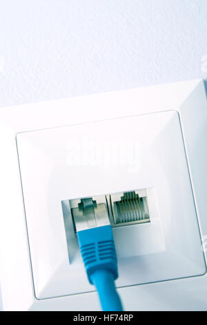 LAN cable plugged into the wall outlet Stock Photo