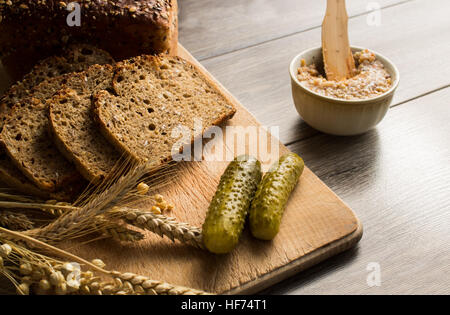 Bread lard and pickles on old wooden cutting board Stock Photo