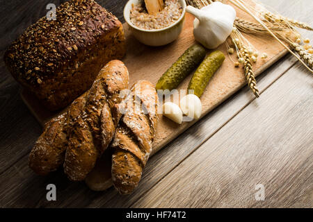 Bread lard and pickles on old wooden cutting board Stock Photo