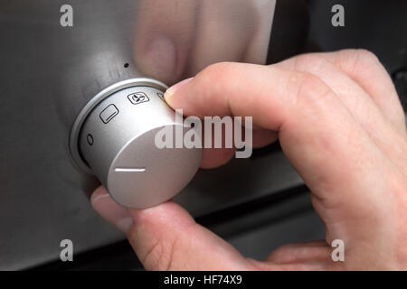 Close up of man hand setting temperature control on oven Stock Photo