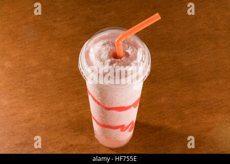 Fresh strawberry smoothie in plastic cup on ceramic floor tile Stock Photo