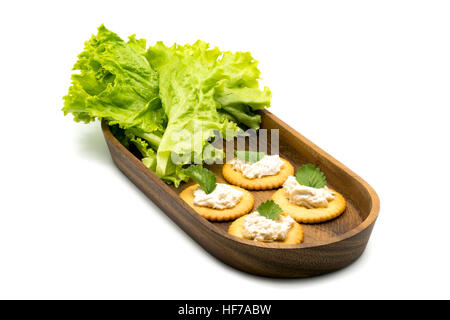 Round crackers with tuna spread and vegetables in wooden tray on white background Stock Photo