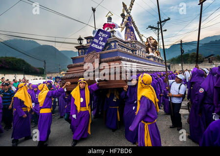 Antigua, Guatemala - April 16, 2014: Man wearing purple robes, carrying a float (anda) during the Easter celebrations in Antigua Stock Photo