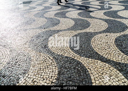 Walking people casting a long shadow on pavement Stock Photo