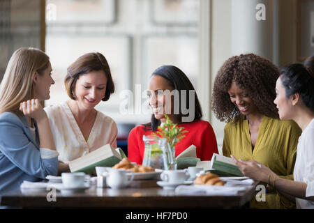 Women friends discussing book club book at restaurant table Stock Photo