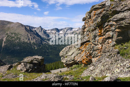 The Rocky Mountains with large lichen covered boulders and glimpse of state highway 34 on a bright summer day. Stock Photo