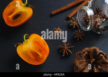 Top flat view: anise star, cinnamon sticks and persimmon Stock Photo