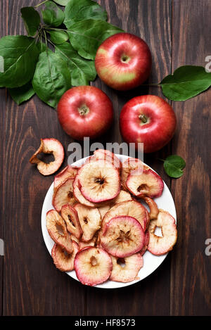 Apple chips and raw fruits on wooden background, top view Stock Photo