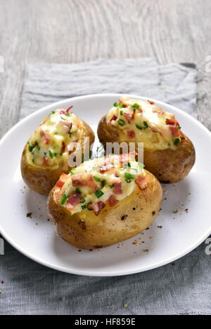 Baked potato with bacon and cheese on white plate Stock Photo