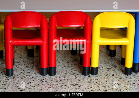 three colored plastic chairs in a nursery for small children Stock Photo
