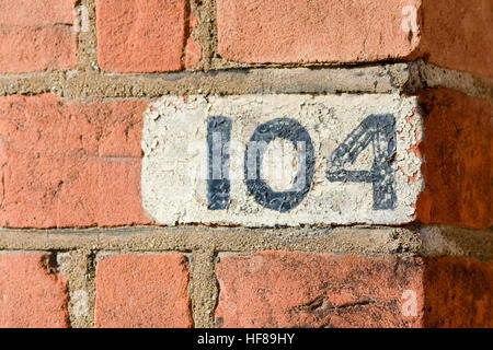 House number 104 sign painted on wall Stock Photo