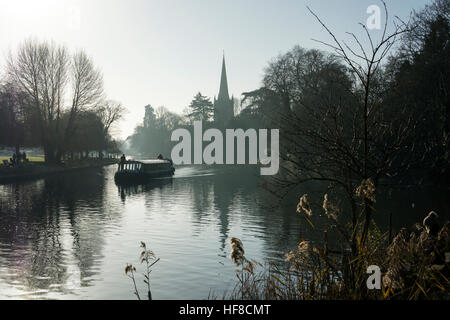 Stratford-upon-Avon, Warwickshire, UK. 28th December 2016. A pleasure trip boat passes along the River Avon near to Holy Trinity Church in the soft winter sunlight. Credit: Colin Underhill/Alamy Live News Stock Photo