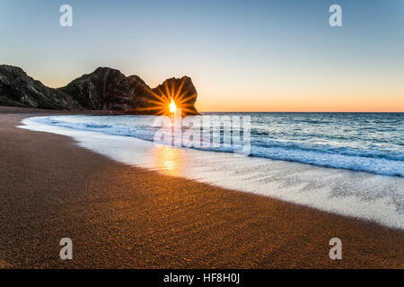 Durdle Door, Lulworth, Dorset, UK.  29th December 2016.  UK Weather.  A sparkling sunrise shines through the limestone arch of Durdle Door on the Dorset Jurassic Coast on a clear December winters morning.  Photo by Graham Hunt/Alamy Live News Stock Photo