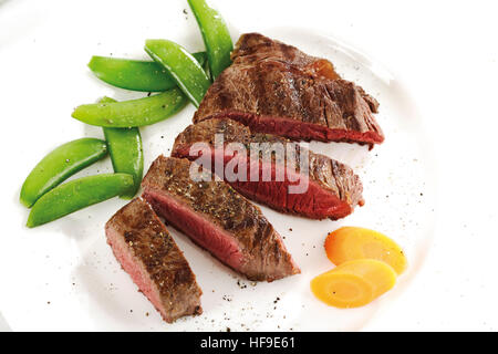 Steak cut into slices with carrots and snow peas Stock Photo