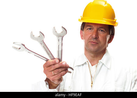 Construction worker wearing yellow hardhat holding wrenches Stock Photo