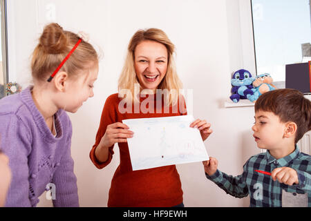 Young woman in red sweater holding child's drawing Stock Photo